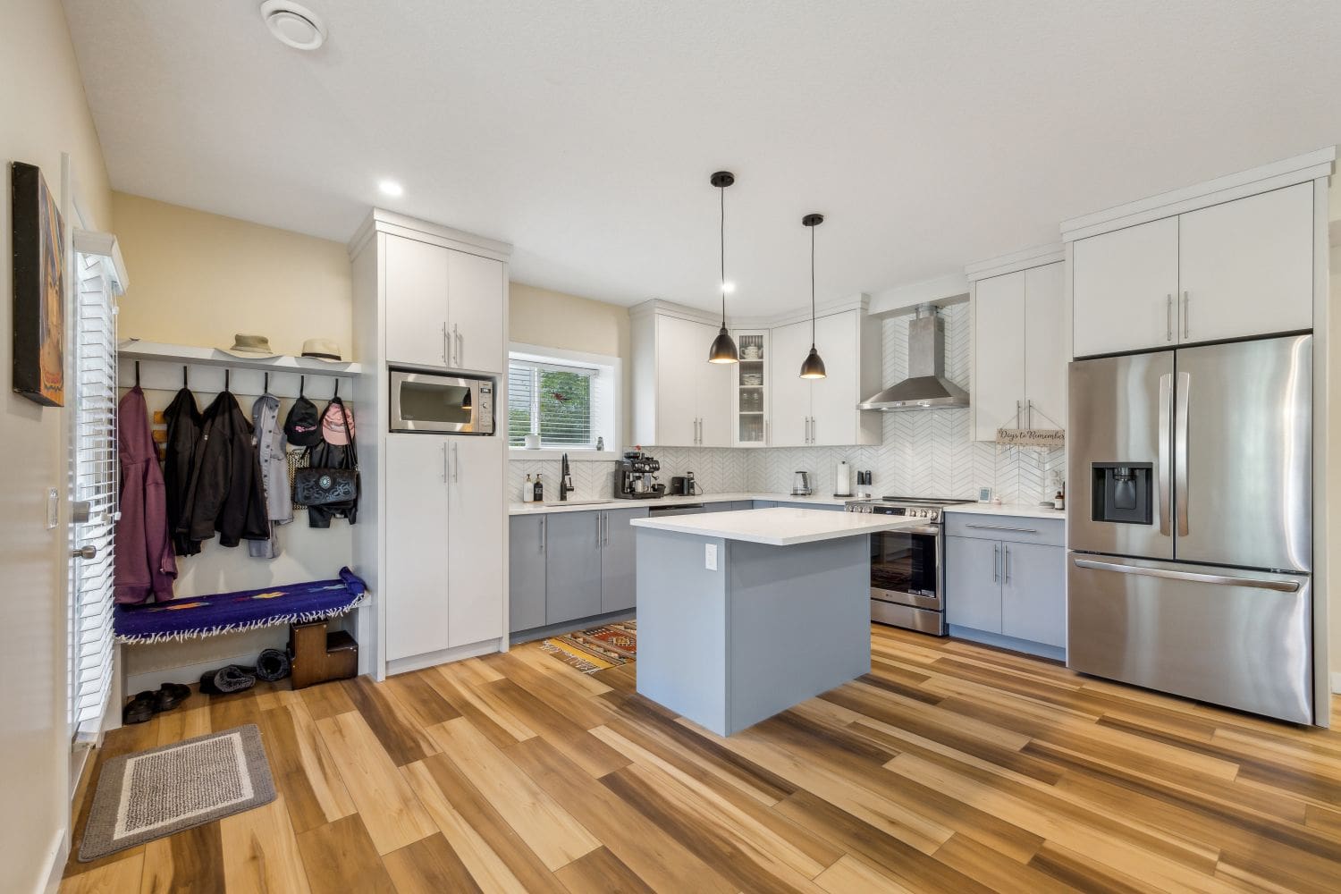 A kitchen with hard wood floors and white cabinets.